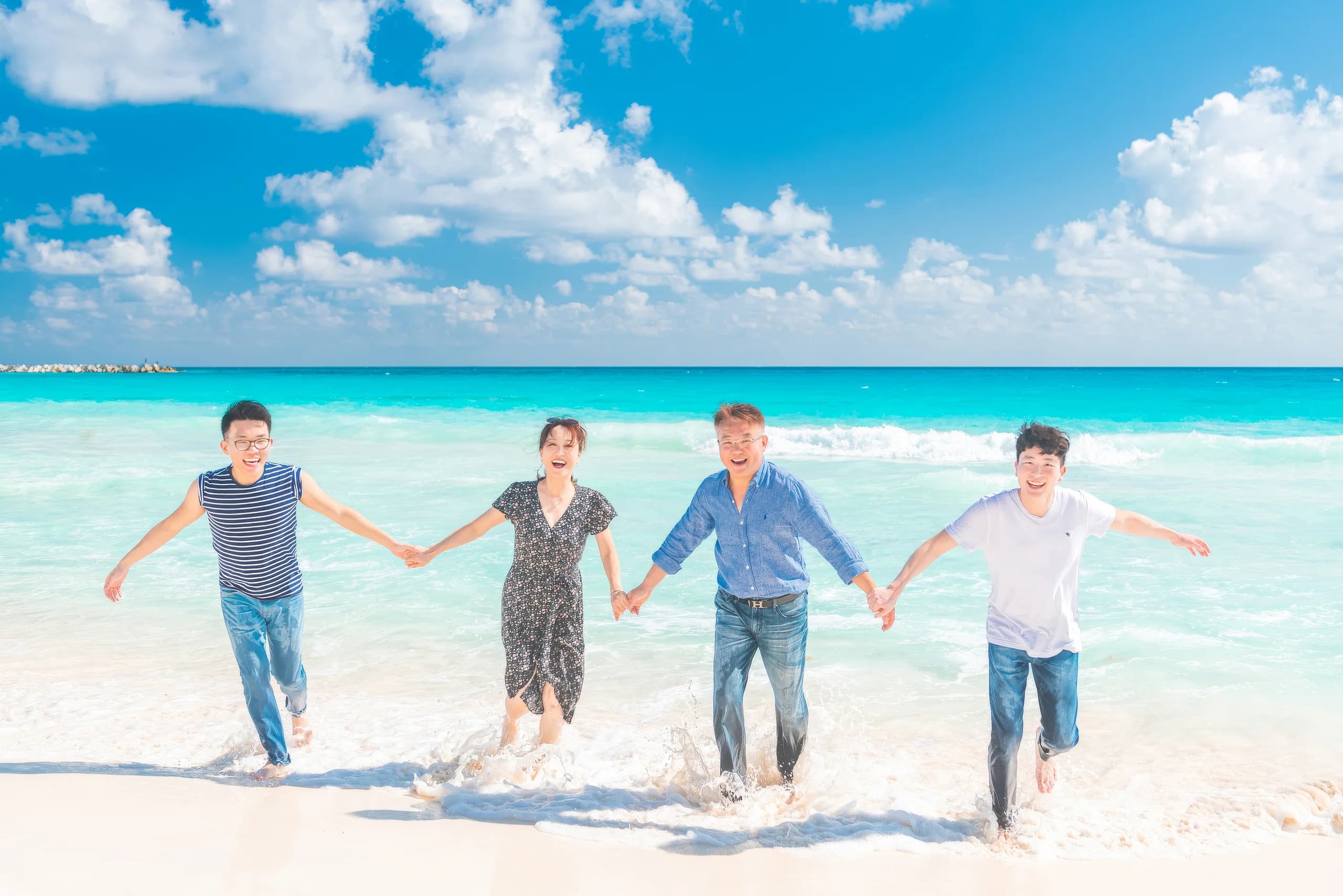 칸쿤 해변을 손잡고 뛰는 가족
