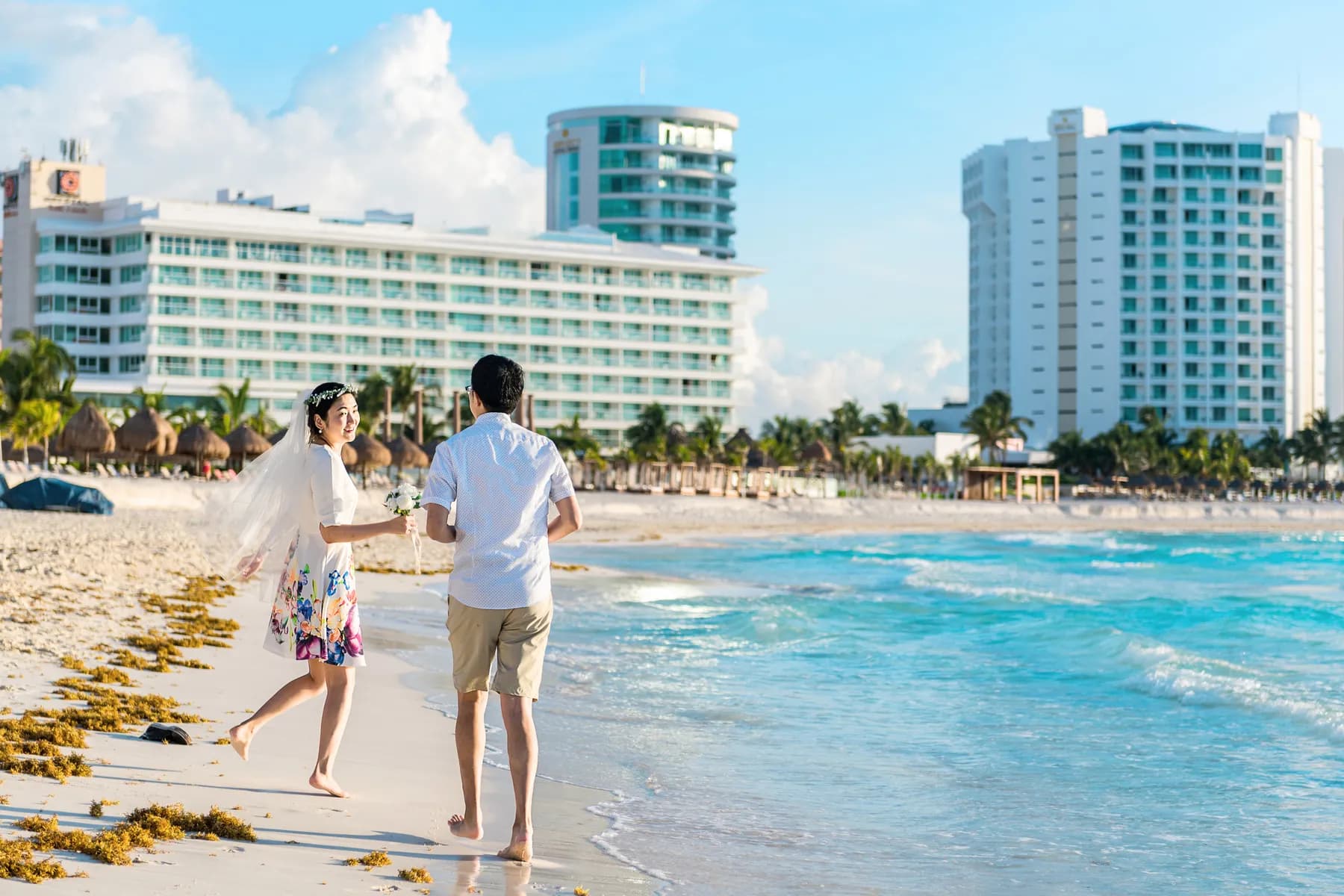 Newlyweds running along the beach in Cancun's Hotel Zone
