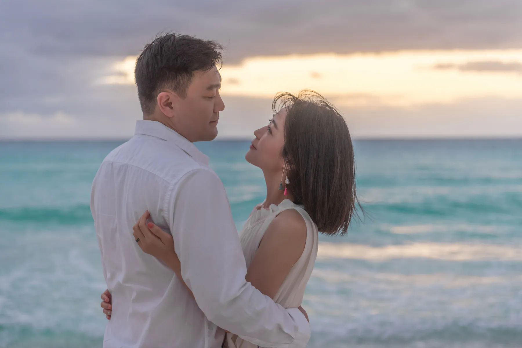 Couple facing each other by the sea in morning light