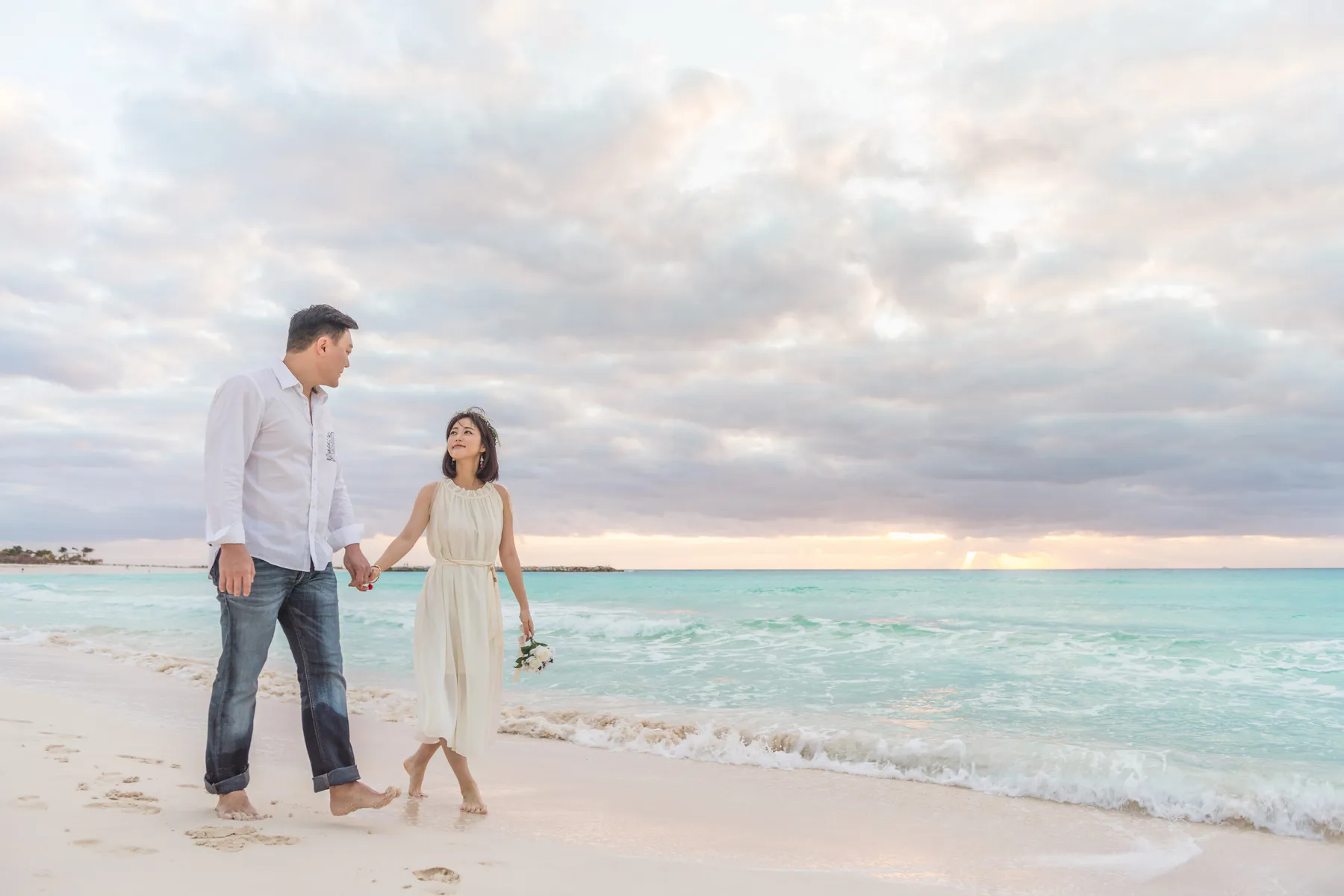 Couple walking together on a cloudy morning beach