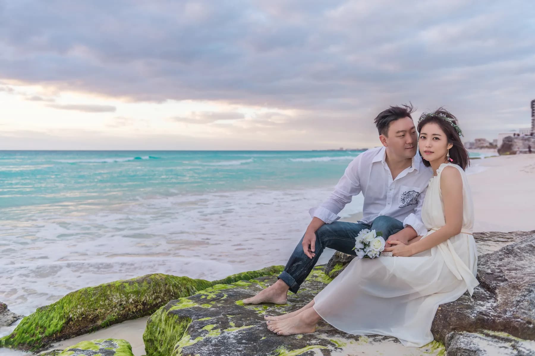 Newlyweds smiling on the rocks by turquoise water