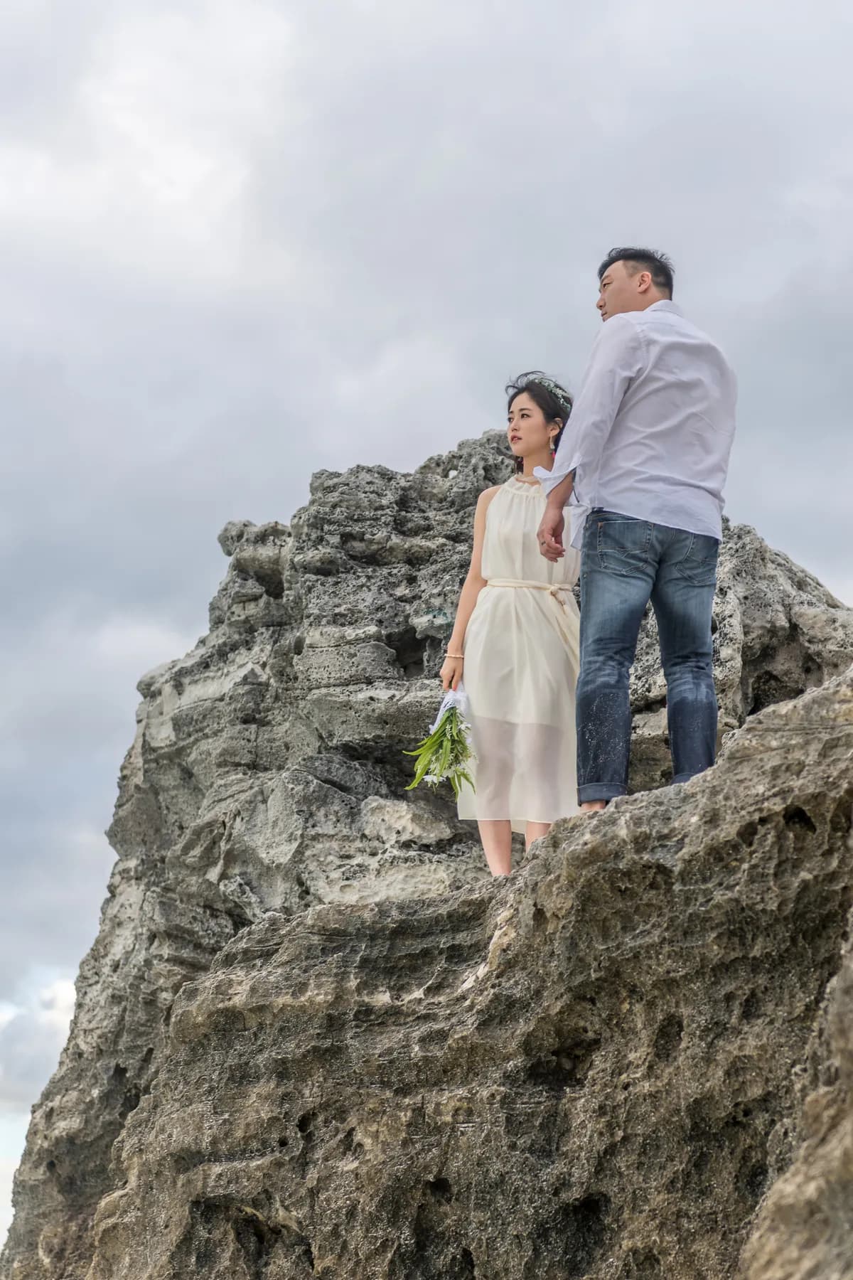 Newlyweds standing on top of a seaside rock
