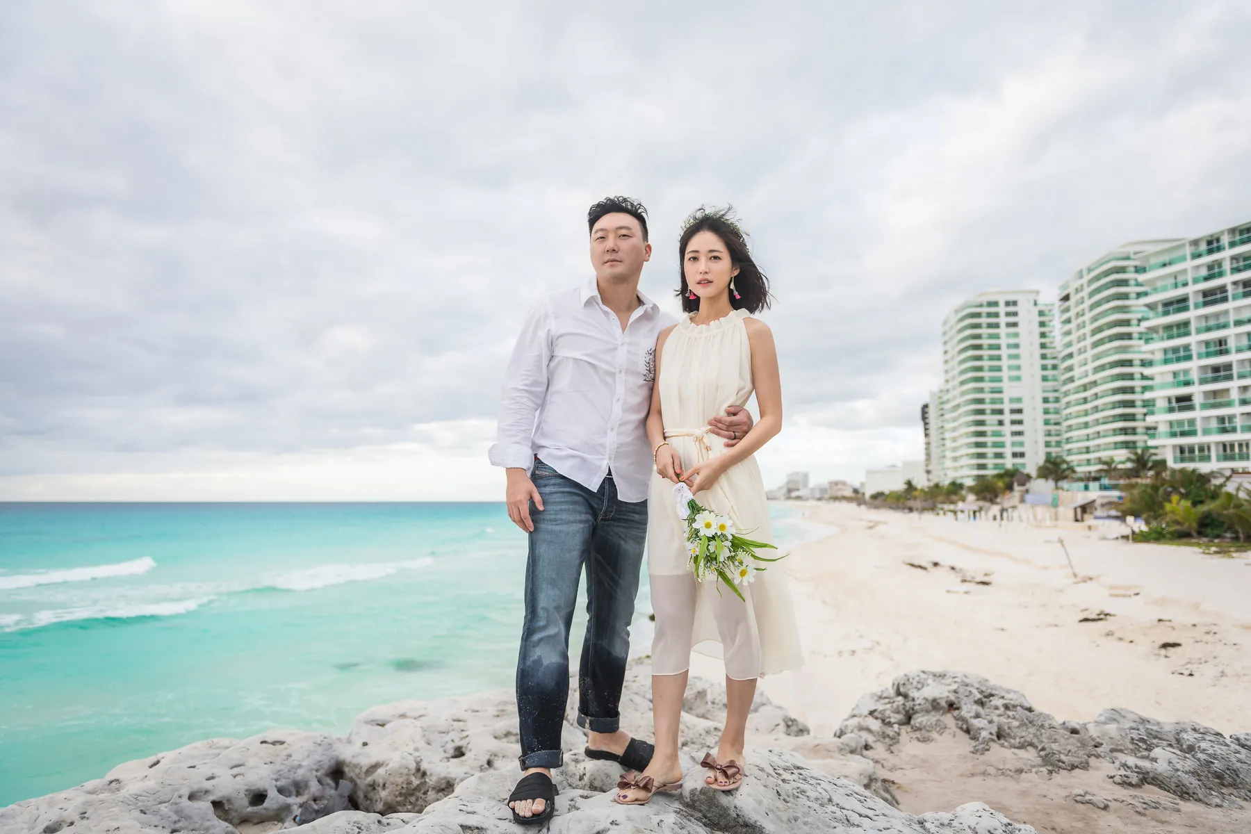 Couple on the rocks with Cancun's Hotel Zone behind them