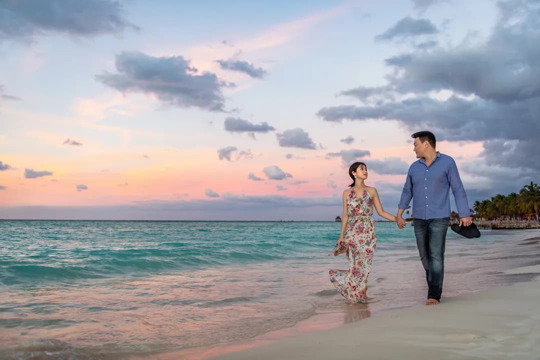 Couple walking on a pink sunset beach on Isla Mujeres