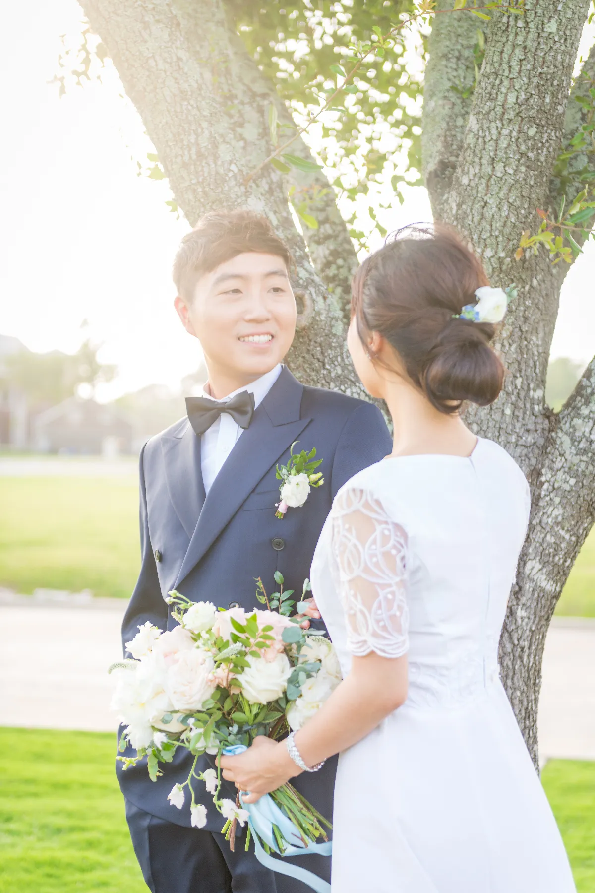 Bride and groom with a bouquet under a tree