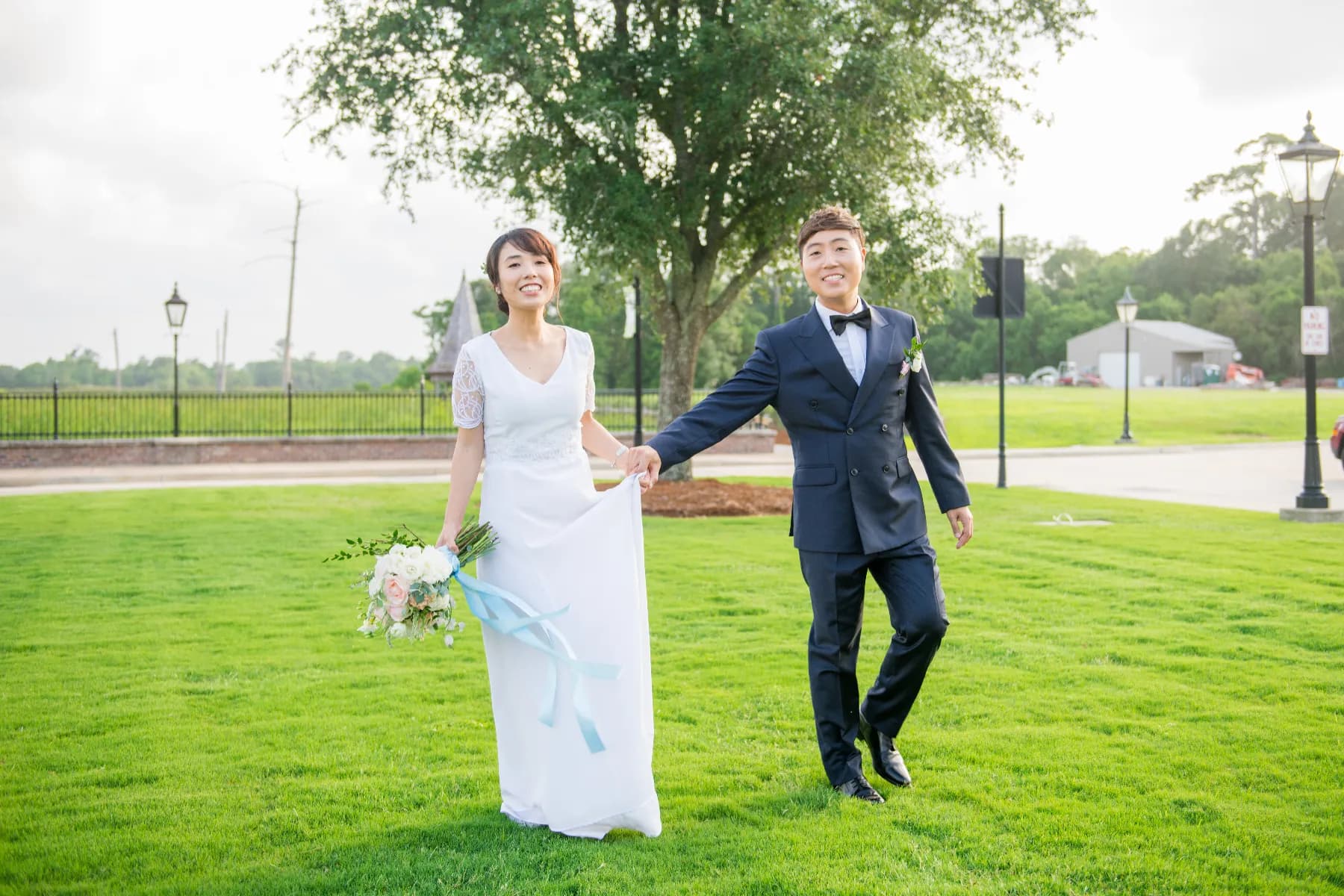 Bride and groom walking hand in hand across the lawn