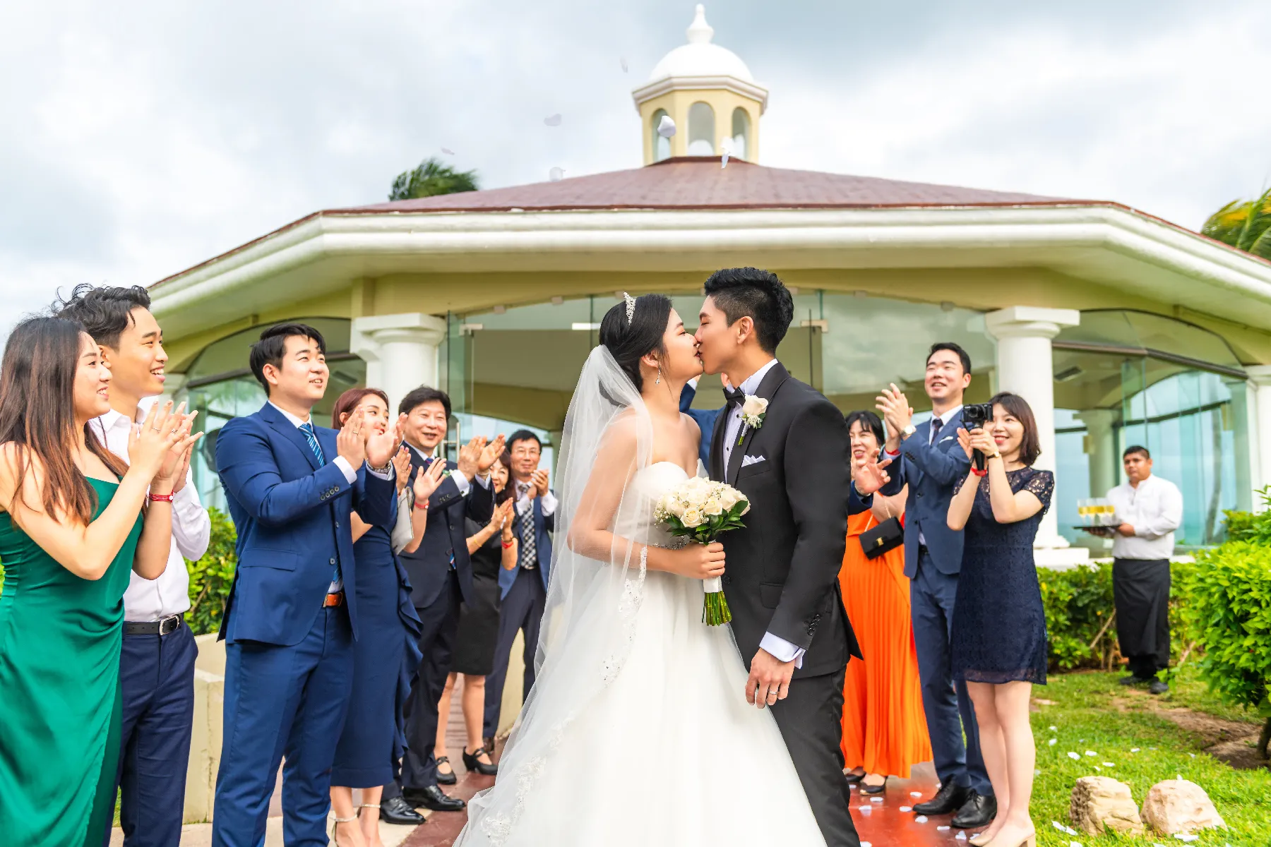 Bride and groom kissing in front of the gazebo as guests applaud